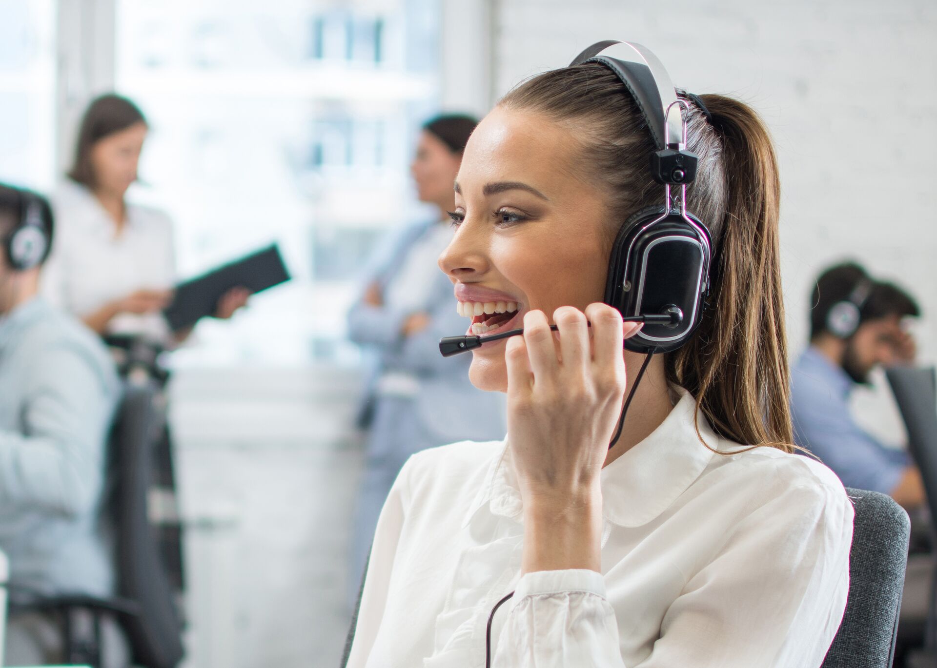 Eine Telefonistin sitzt an ihrem PC-Arbeitsplatz in der Agentur und nimmt Telefonate an.