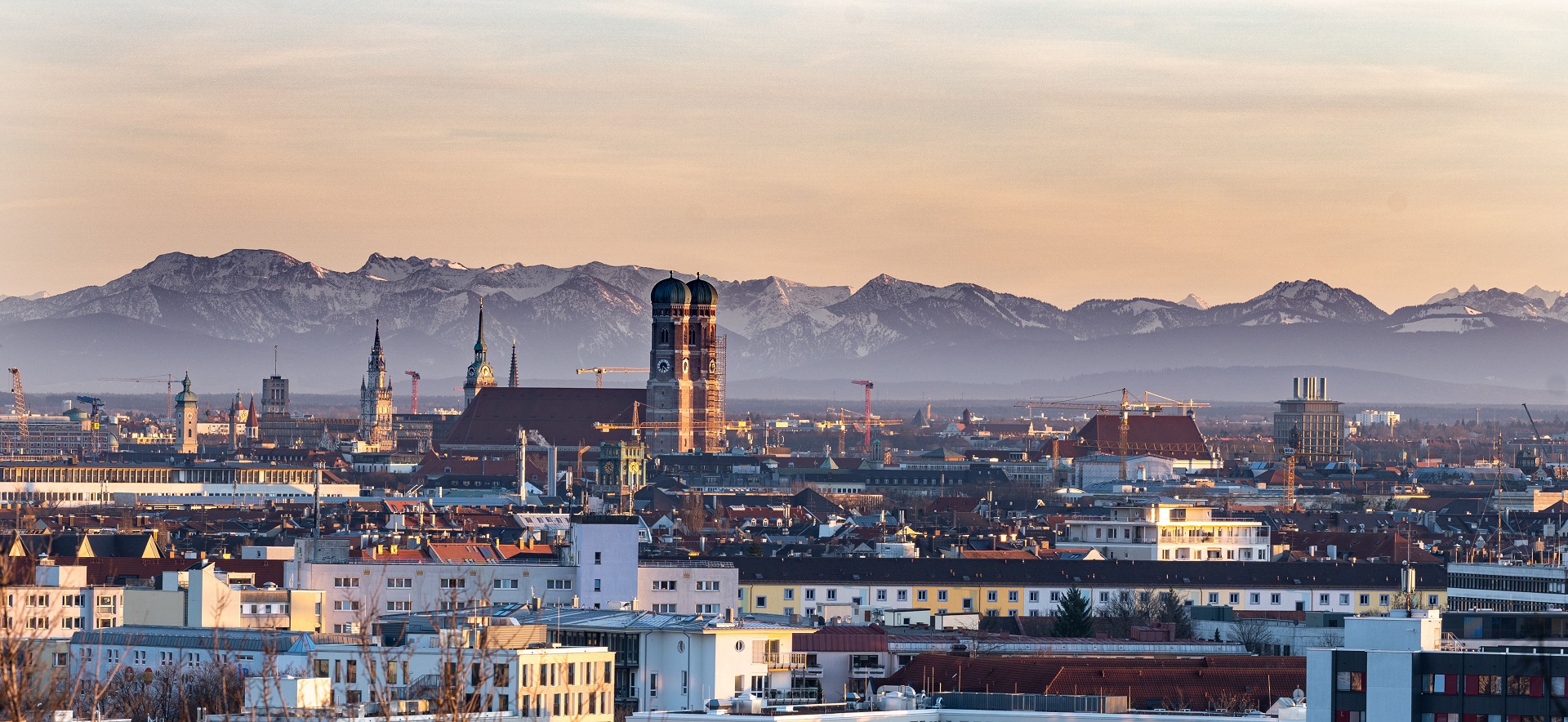 Blick über die Dächer von München mit den Alpen im Hintergrund